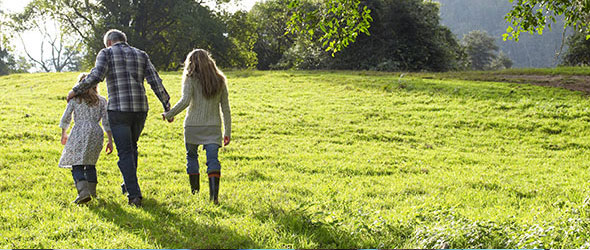 Family walking away from camera through a grass field