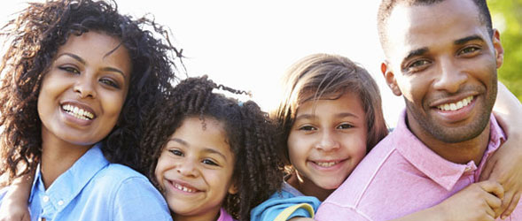 Young family with two kids, smiling at camera